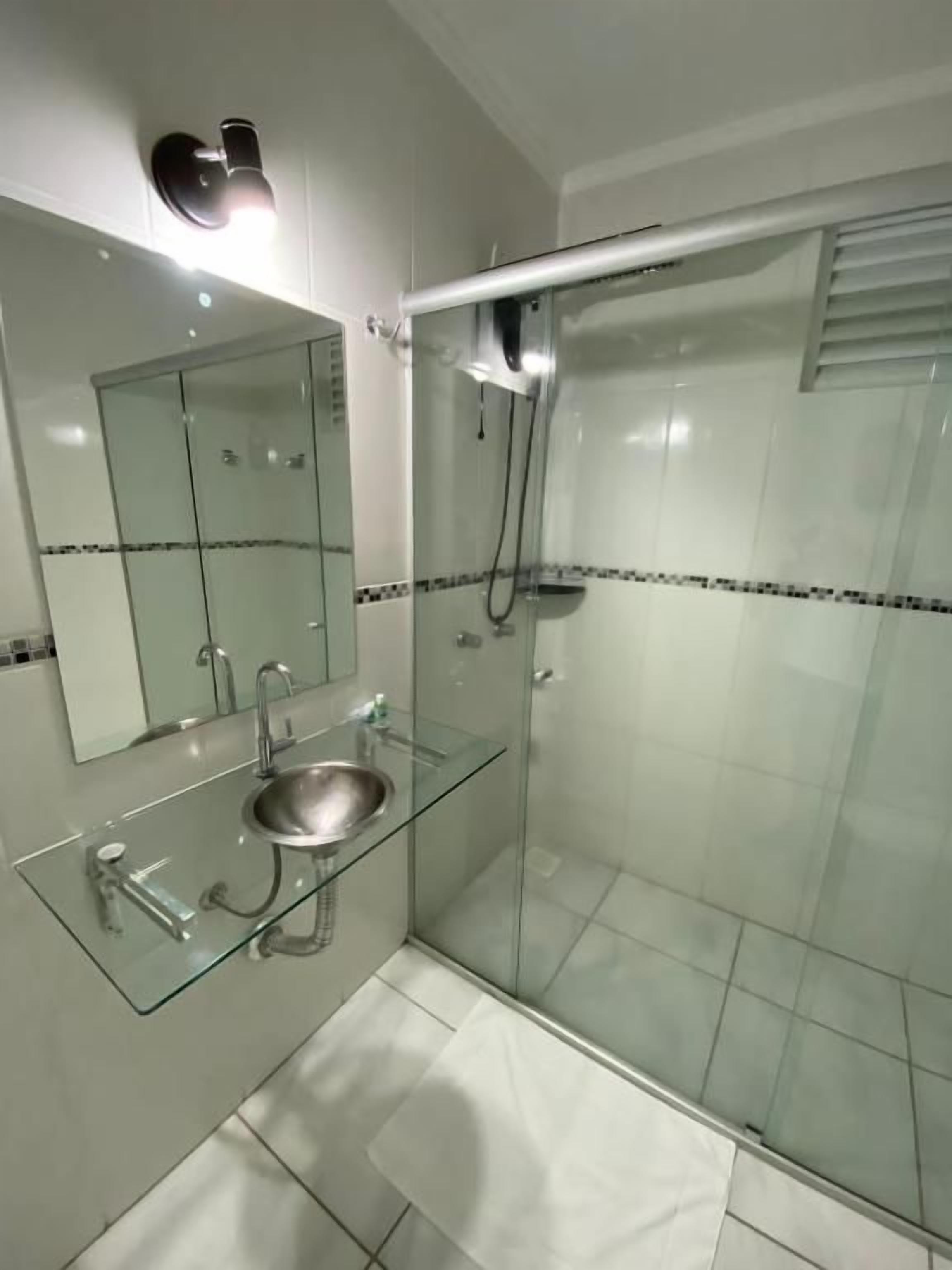 Een moderne badkamer met een douchecabine van glas, een glazen wastafel en een spiegel.