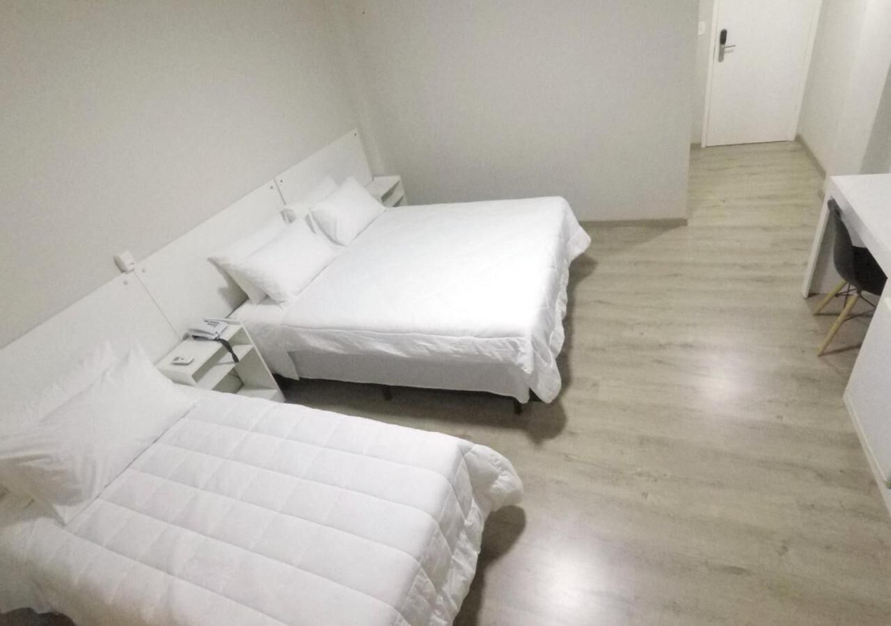 A room with two beds, a desk, and a chair.