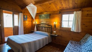 Eine Hütte mit zwei Betten, einem Moskitonetz und einem kleinen Tisch mit einer Lampe.