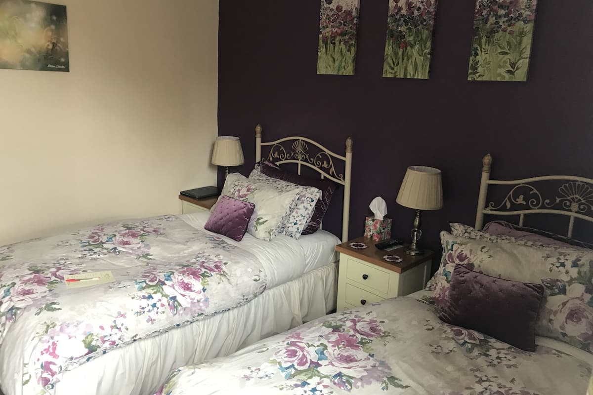 A double bed with floral bedding, two bedside tables with lamps, and a headboard.