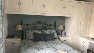 A bedroom with a bed, two bedside tables, a desk, and a wardrobe.