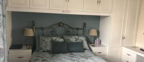 Un dormitorio con cama, dos mesitas de noche, un escritorio y un armario.