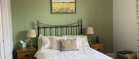 Un dormitorio con cama, dos mesitas de noche, una lámpara, un cuadro y una araña.
