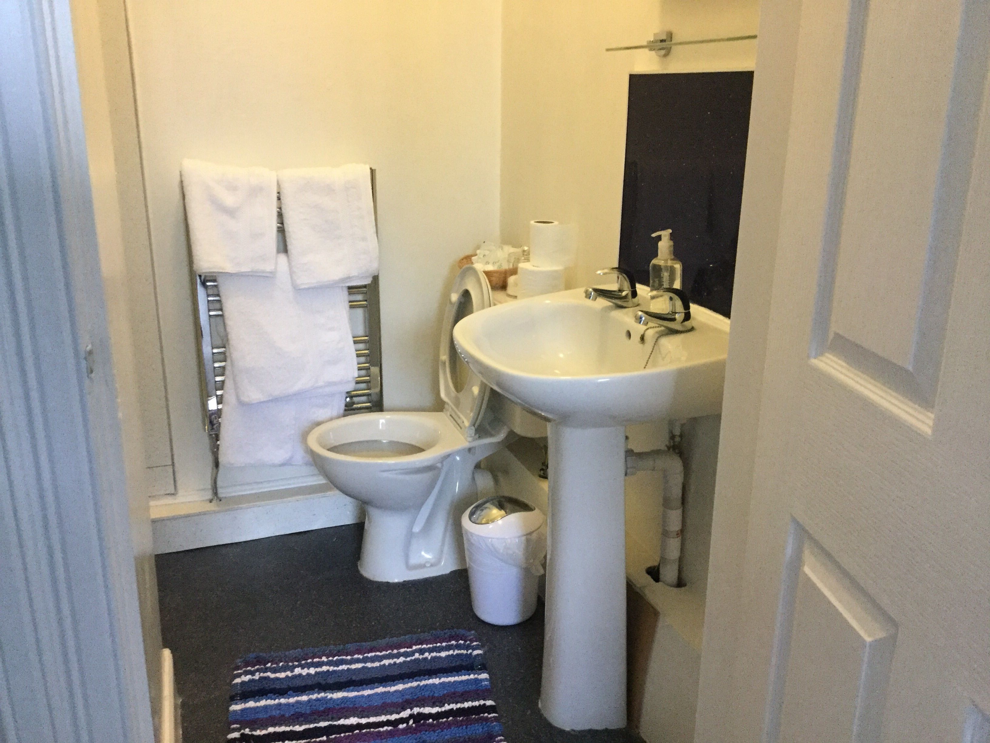 Ein kleines Badezimmer mit Toilette, Waschbecken und Handtuchhalter.