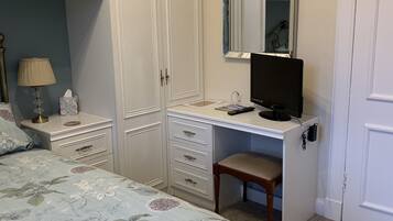 A bedroom with a bed, a desk, a chair, a wardrobe, and a mirror.