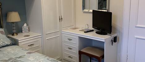 A bedroom with a bed, a desk, a chair, a wardrobe, and a mirror.