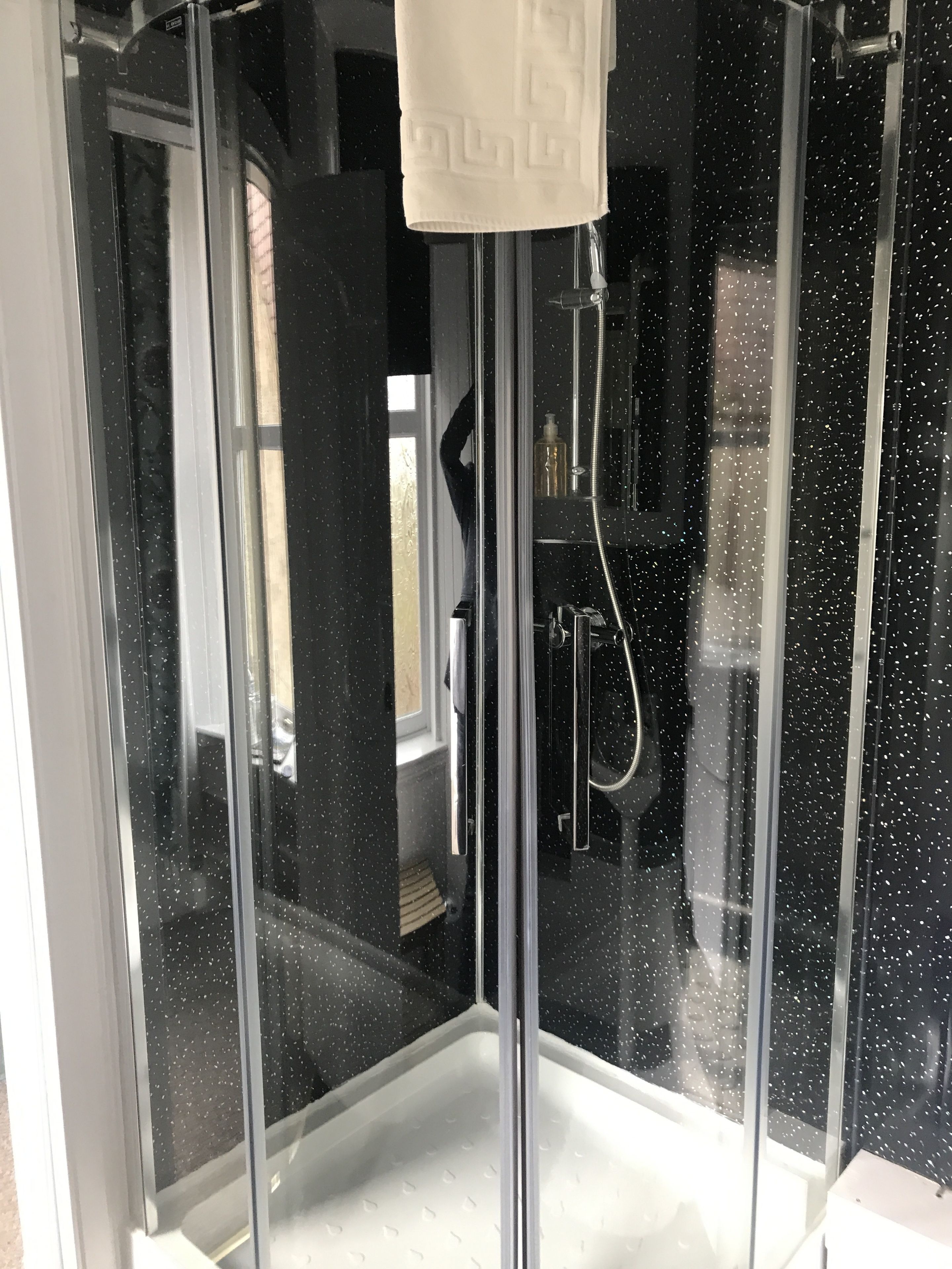 A glass-enclosed shower area with a white towel hanging on a rack.