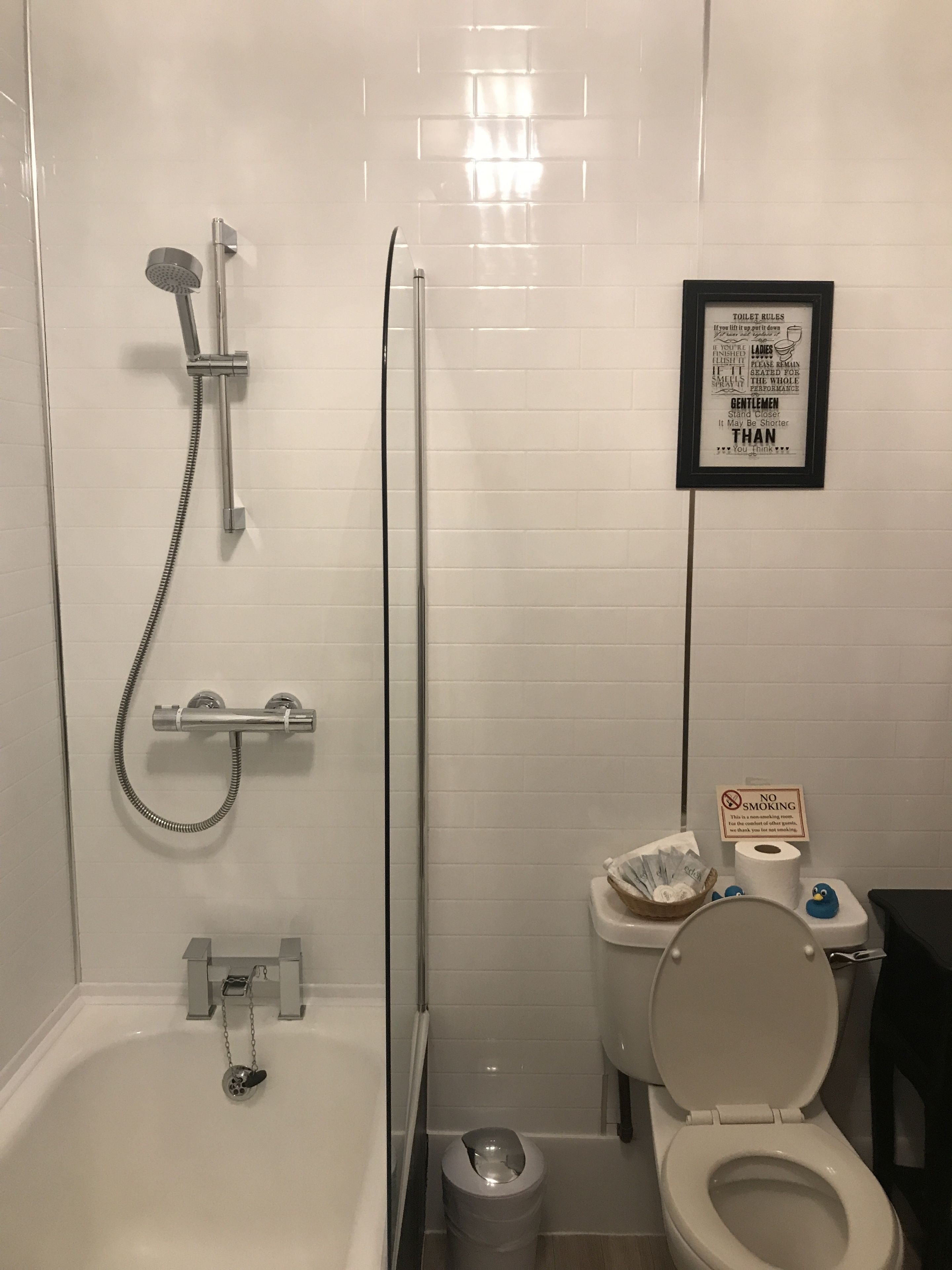 Une salle de bain avec une baignoire, une douche, des toilettes et un panneau encadré accroché au mur.