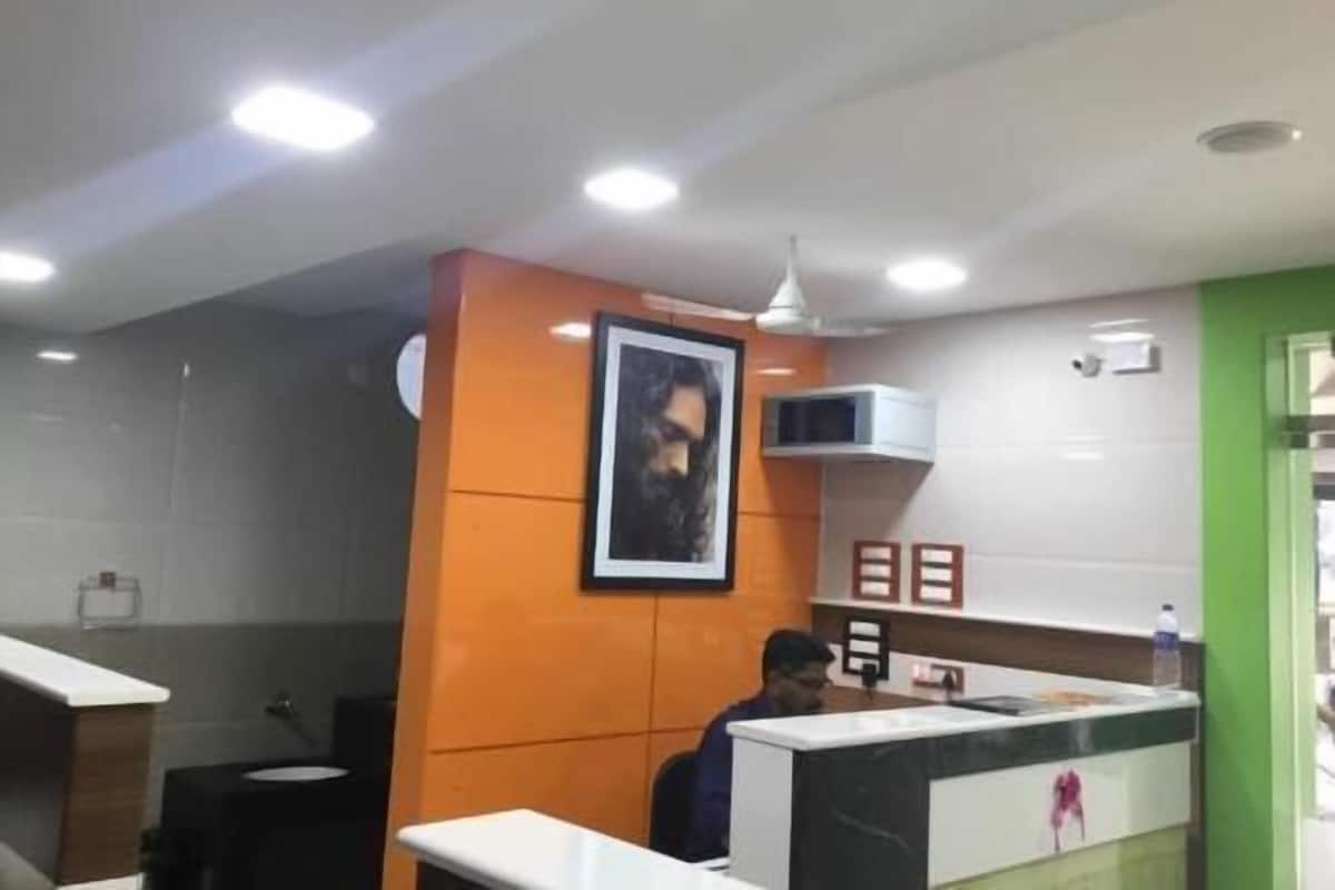 A hotel reception area with a counter, a framed picture on the wall, and a person seated behind it.