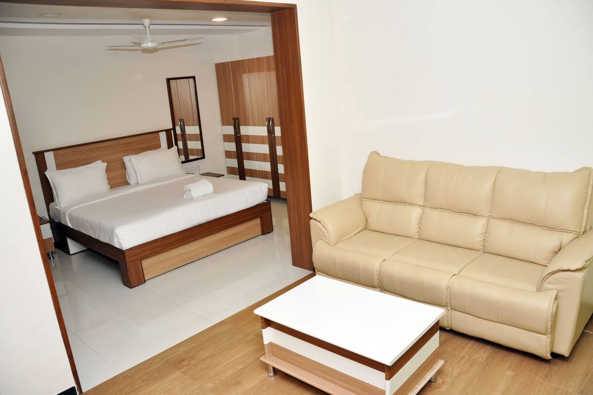 A bedroom with a bed, a beige sofa, and a white coffee table.