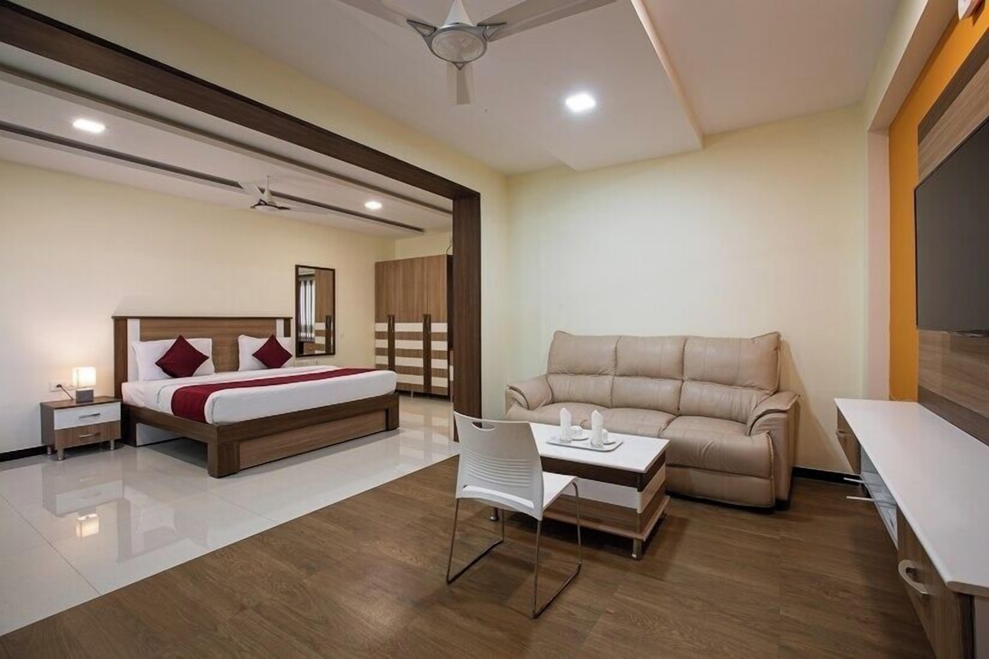 A modern hotel room with a bed, a sofa, a desk, and a chair.