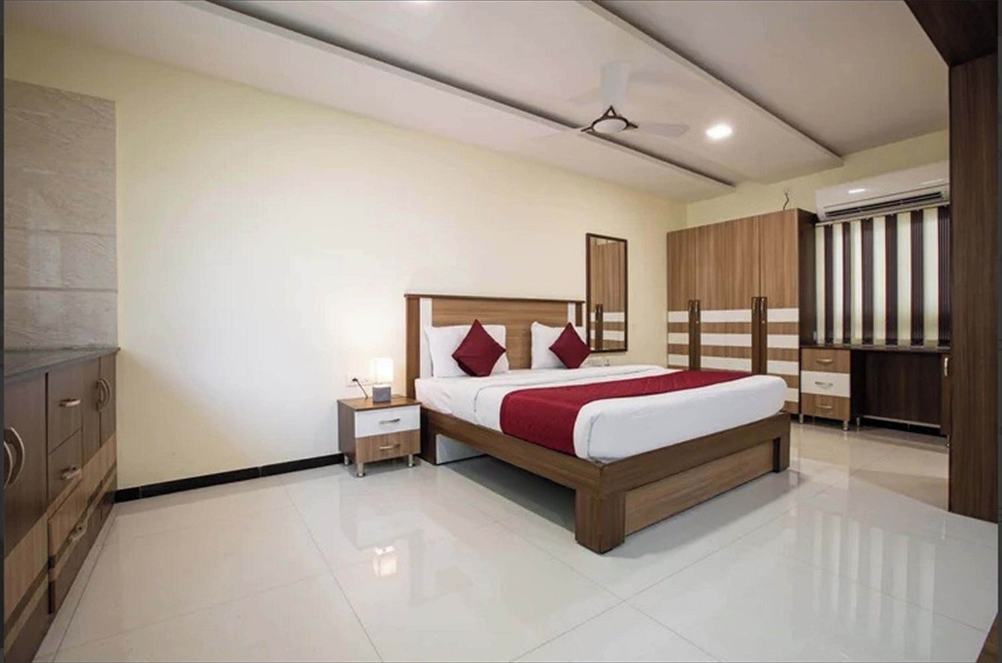 A modern bedroom with a large bed, wooden wardrobe, and a nightstand.
