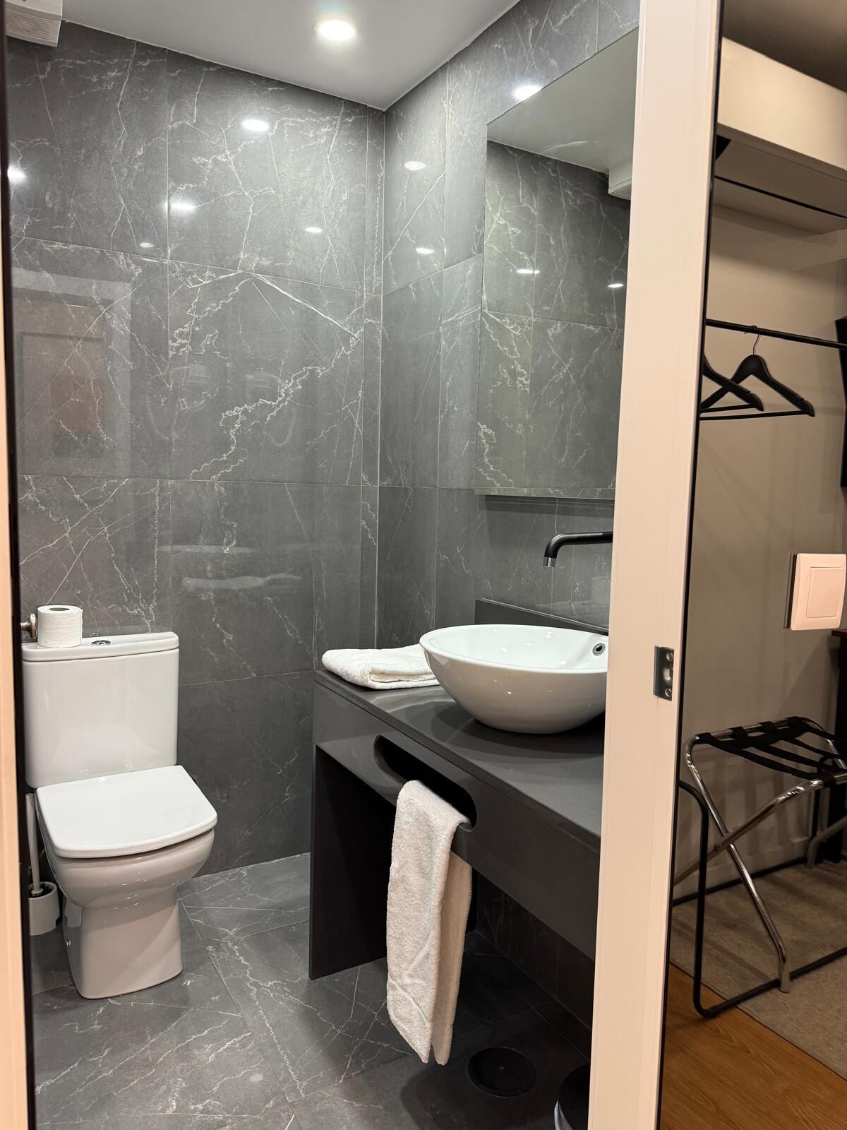 Uma casa de banho moderna com sanita, lavatório e barra para toalhas.