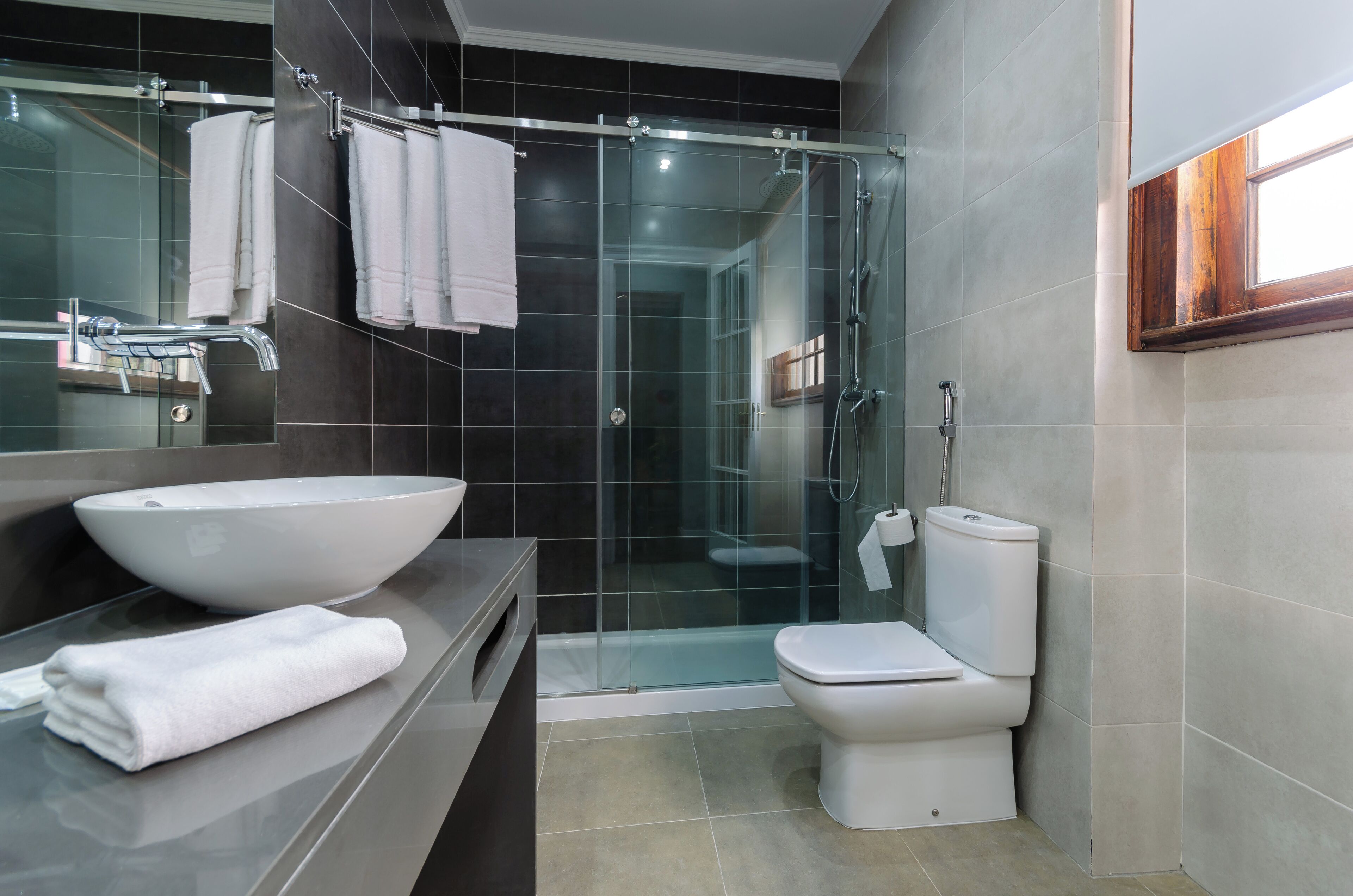 Een moderne badkamer met een glazen douchecabine, een wit wastafelmeubel en een toilet.
