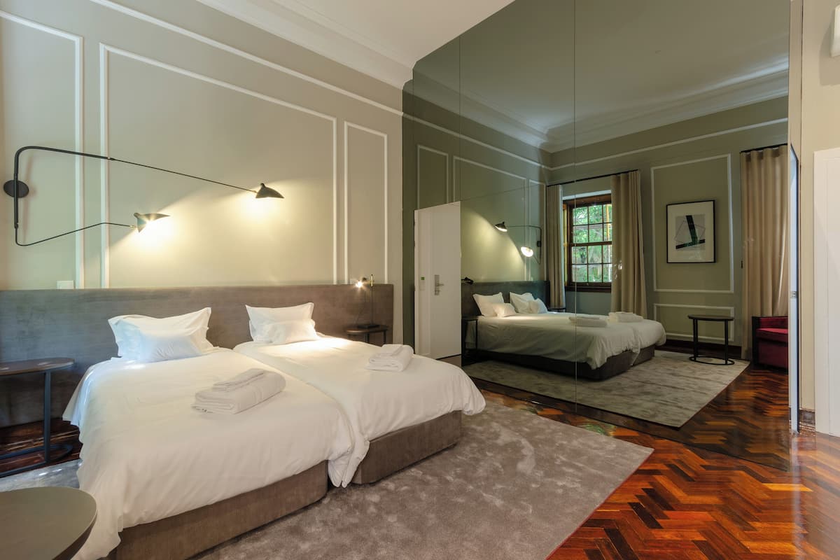 A hotel room with two beds, a large mirror, and a view of the outdoors.