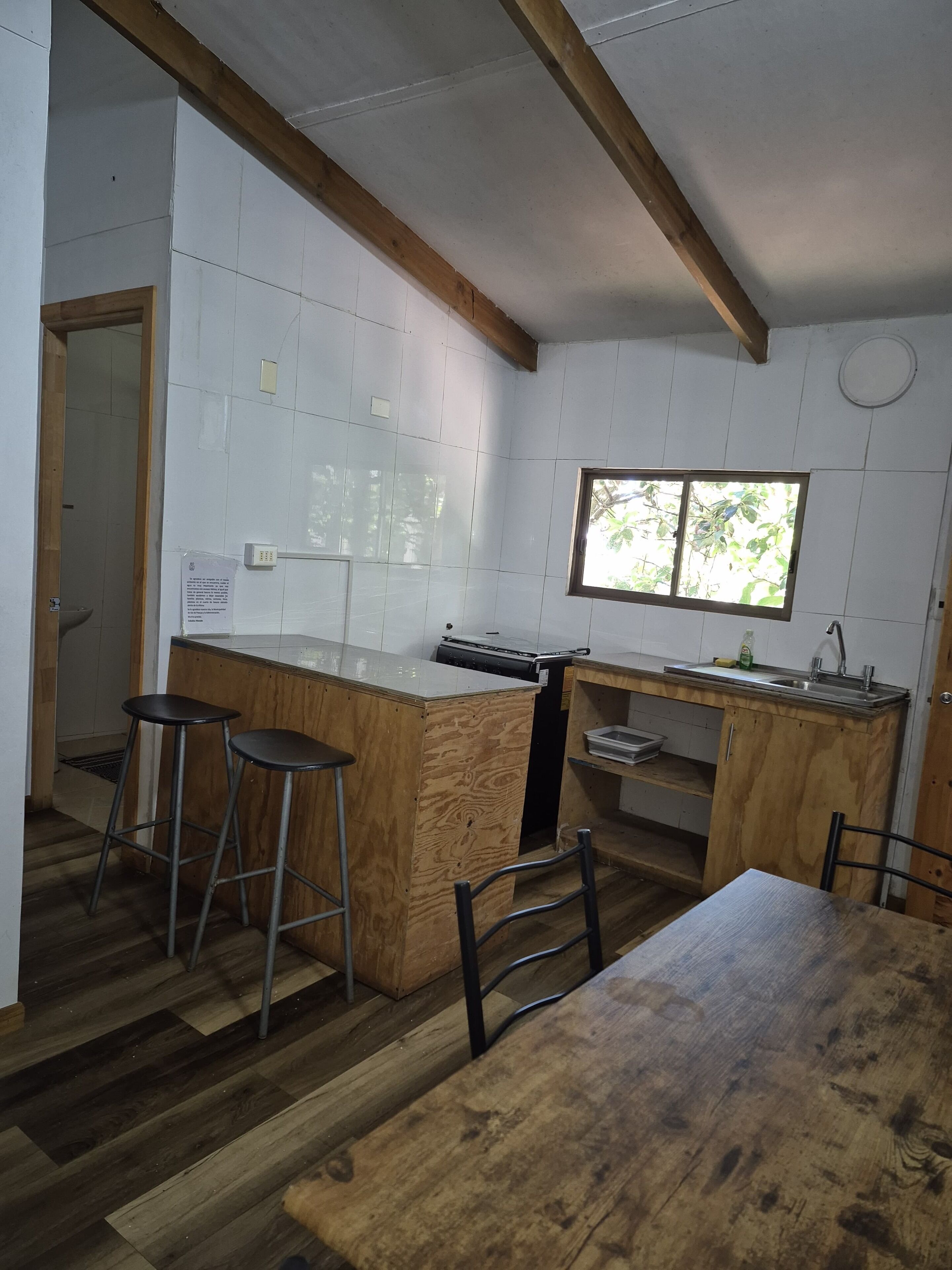 A kitchen with a wooden island, bar stools, a dining table, and a window.