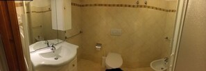 Un baño con lavamanos, inodoro, bidé y zona de ducha.