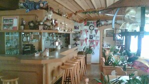 A cozy kitchen with a bar area, wooden stools, and various kitchen appliances. - Landgasthaus Gemsennest (Feldberg)