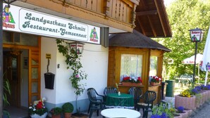 A restaurant with outdoor seating, a signboard, and potted plants. - Landgasthaus Gemsennest (Feldberg)