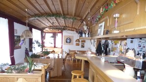 A cozy kitchen with wooden furniture, a bar area, and various kitchen appliances. - Landgasthaus Gemsennest (Feldberg)