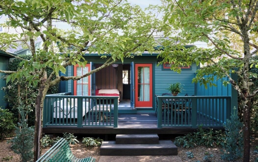 A small, two-story house with a porch and a front door.