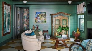 A room with a checkered floor, a sofa, a wooden cabinet with plants, and artwork on the walls. - Cottages at Little Saint (Healdsburg)
