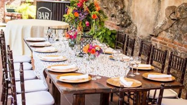 An outdoor dining area with a long table set for a meal, surrounded by wooden chairs. - Hotel La Casona de Antigua (Antigua Guatemala)
