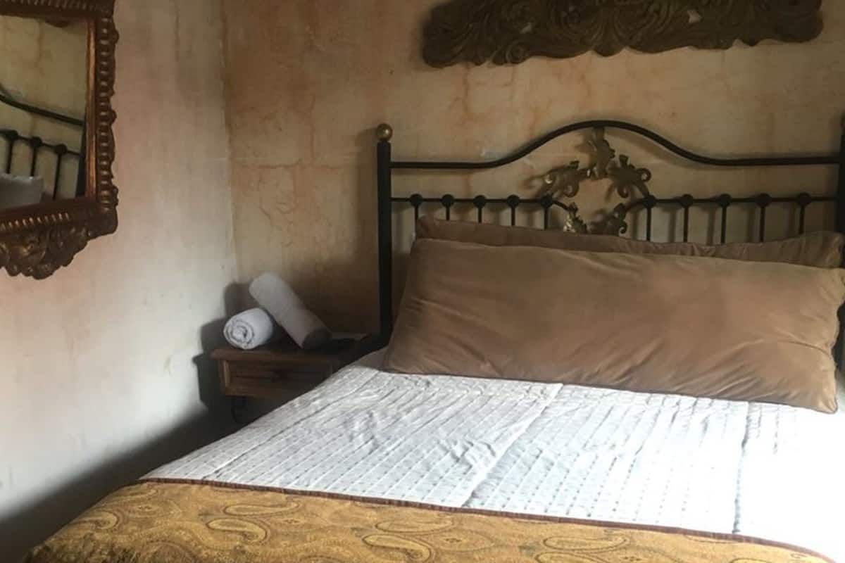 Ein Schlafzimmer mit einem Bett, einem Nachttisch, einem Spiegel und einem Wandbild.