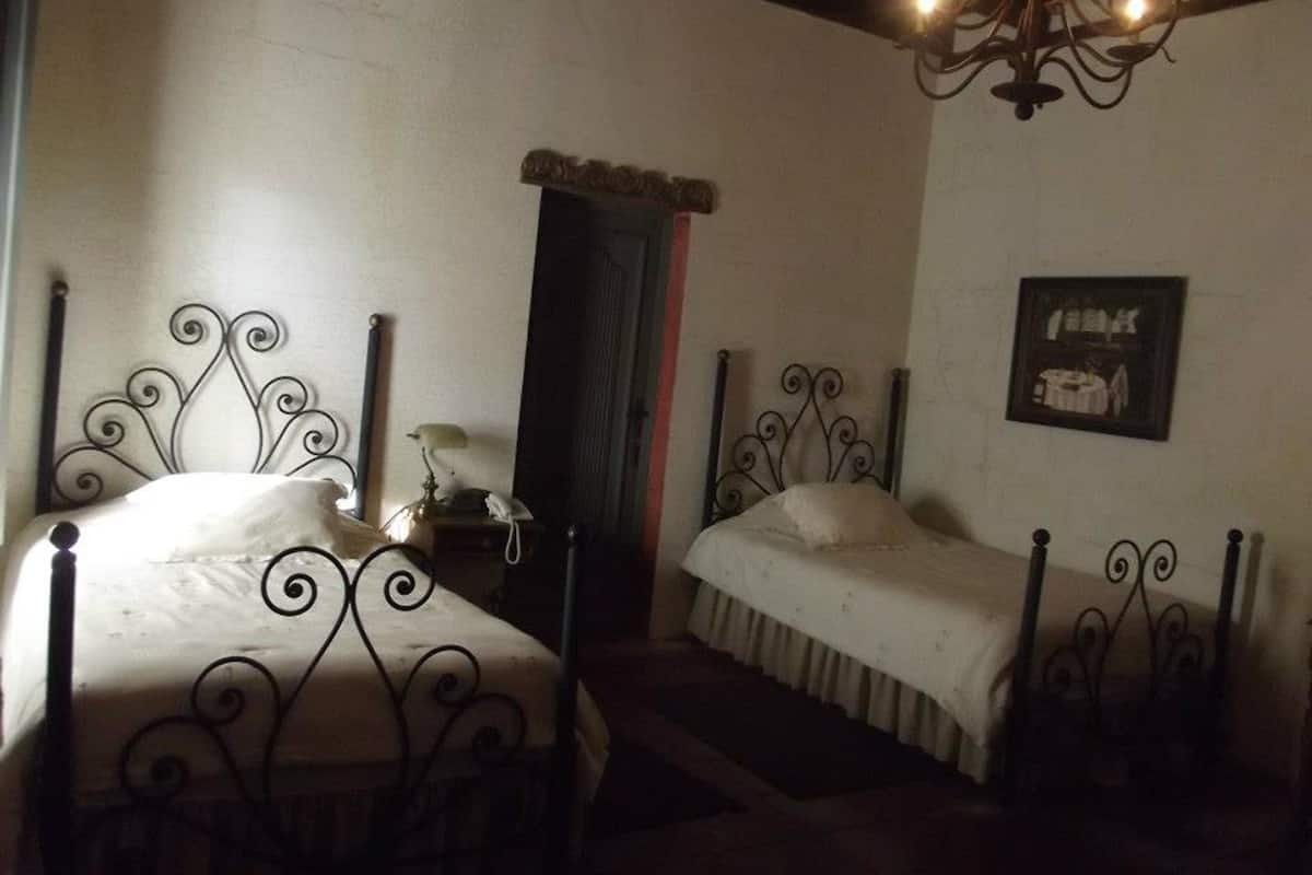 Ein Zimmer mit zwei Betten, einer Kristalllüster, einer Tür und einem gerahmten Bild an der Wand.