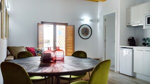 A dining area with a round wooden table, green chairs, and a wooden ceiling. - Rúa Travesa (Santiago de Compostela)