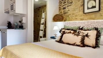 A bedroom with a bed, a dresser, a microwave, and a stone wall.
