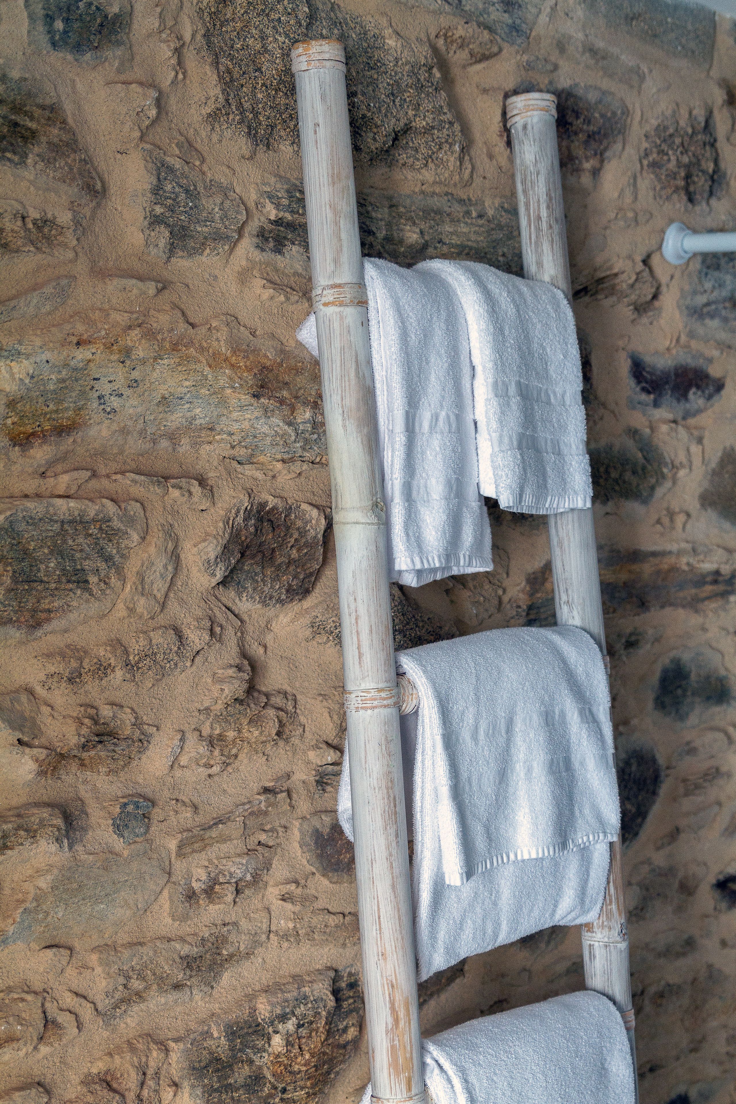 Una escalera de madera con toallas colgadas frente a un muro de piedra.