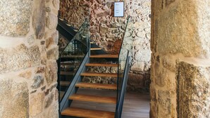 A staircase with wooden steps and black metal railings, leading to a stone wall. - In Barcelos Hostel & Guest House (Barcelos)