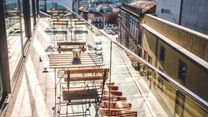 A rooftop terrace with tables and chairs, a clear view of the cityscape, and a building with a modern facade. - In Barcelos Hostel & Guest House (Barcelos)
