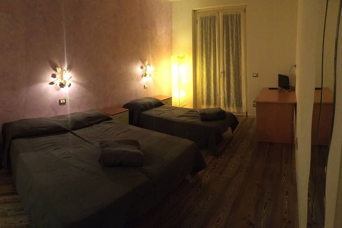 A hotel room with two beds, a desk, and a nightstand.