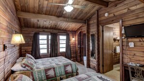 A cabin-style bedroom with two beds, a ceiling fan, and a television. - Rib Waters Inn (Rib Lake)