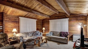 A log cabin interior with two sofas, a coffee table, and a television. - Rib Waters Inn (Rib Lake)