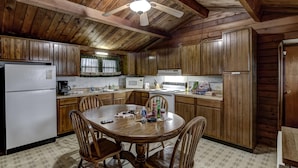 A kitchen with wooden cabinets, a central island with chairs, a ceiling fan, and a refrigerator. - Rib Waters Inn (Rib Lake)