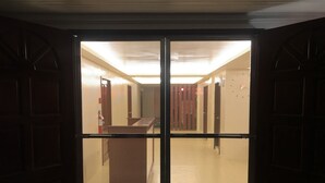 Een hotel lobby met een grote glazen deur, een receptiebalie en een trap naar de verdiepingen erboven.
