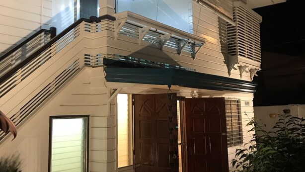 Een tweelaags huis met een overdekte veranda, een trap en een groot raam.