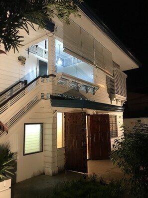 Une maison à deux étages avec un porche couvert, un escalier et une grande fenêtre.