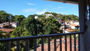 Un balcón con vistas a una zona residencial, que incluye casas y una colina con un faro.