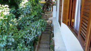 Una estrecha escalera de piedra que lleva a un edificio blanco con contraventanas de madera.