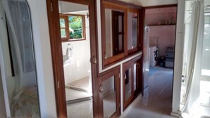 Un pasillo con armarios de madera, una lavadora y una ventana con vistas a zonas verdes.