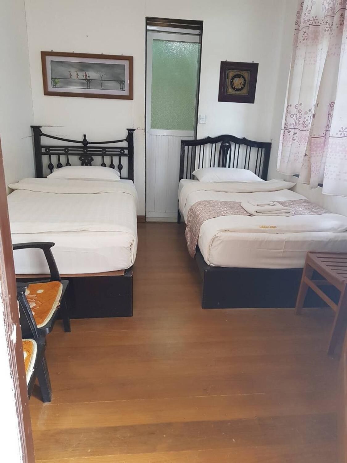 Ein Zimmer mit zwei Betten, einem Sessel und einer Tür.