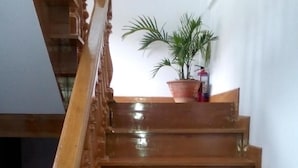 Een houten trap met een leuning en balustrades, die uitkomt op een plateau met een potplant.
