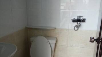 A small bathroom with a toilet, a sink, and a shower attachment.