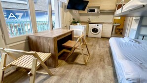Une petite pièce comprenant un lit, un bureau, un lave-linge et un téléviseur.