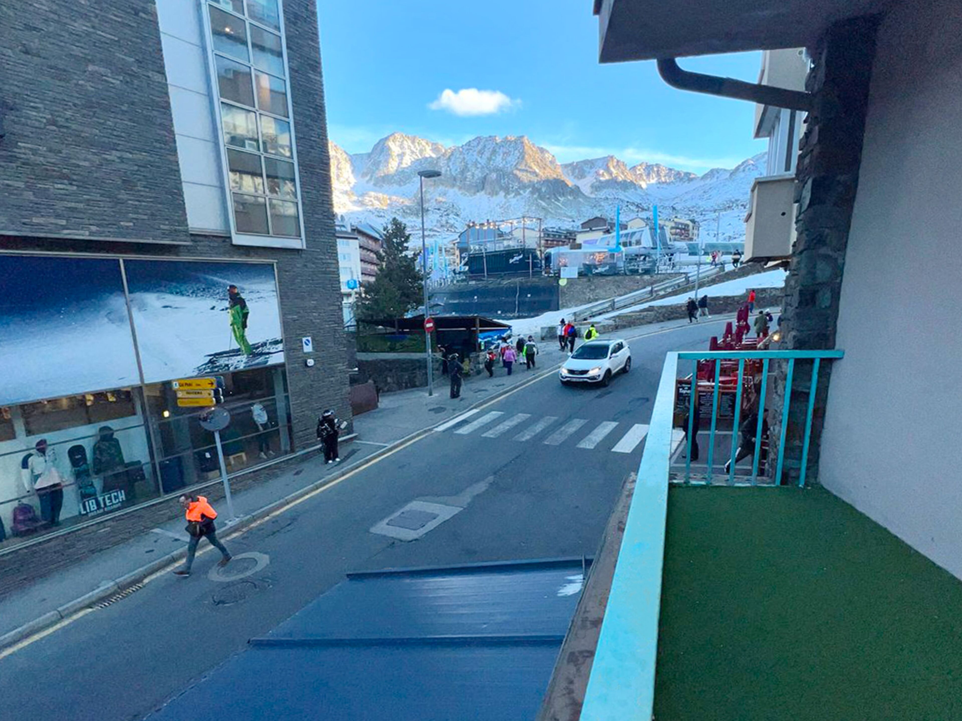 A street view with a building featuring a large window and a mountain backdrop.