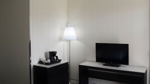 A hotel room with a flat-screen TV on a stand, a bedside table with a lamp and a coffee maker, and a wall-mounted TV. -  VOW MOTEL LISTOWEL ON (North Perth)